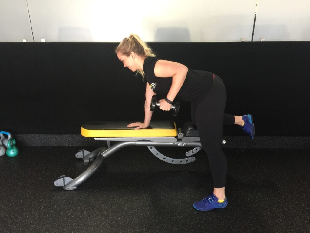 Chuze personal trainer performing triceps kickbacks on the bench