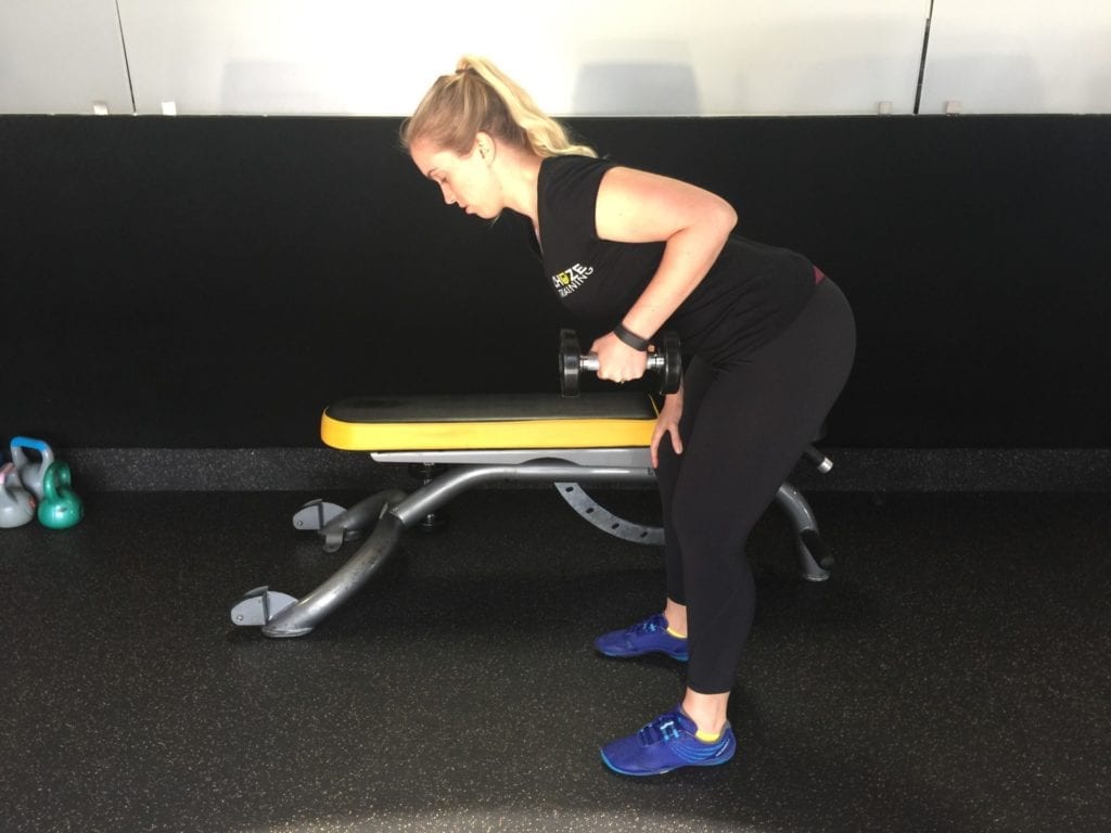 Personal trainer performing triceps kickbacks on leg